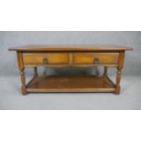 A mid century oak low table in the Jacobean style with magazine shelf to the base. H.47 W.107 D.54cm