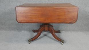 A Regency mahogany drop flap Pembroke table on quadruped swept supports terminating in brass cap