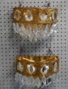 A pair of gilt metal wall lights with crystal drops.