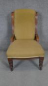 A Victorian walnut upholstered nursing chair on turned tapering supports.