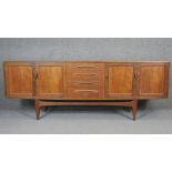 A vintage teak sideboard with central bank of drawers flanked by sliding cupboard doors on shaped