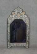 A Moroccan wall mirror in a metal embossed frame. H.88 W.46cm