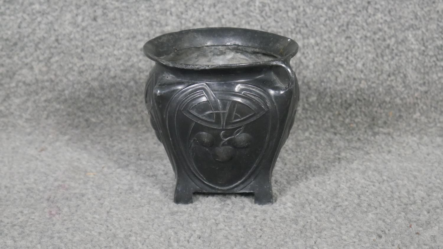 An Art Nouveau twin handled patinated pewter vase with stylised foliate and cherry design, on four