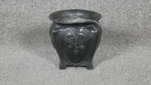 An Art Nouveau twin handled patinated pewter vase with stylised foliate and cherry design, on four