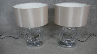 A pair of contemporary table lamps with hooped chrome bases.
