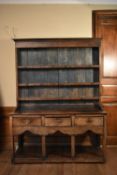 An 18th century country elm dresser of compact size with upper plate rack above three drawers on