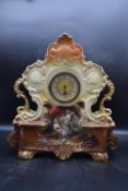 An Edwardian handpainted ceramic mantel clock, central plaque painted with two figures, signed 'Henn