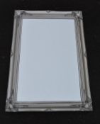 A wall mirror in silvered floral frame. H.90 W.64cm