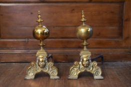 A pair of 19th century brass fire dogs with ball and finials above mask decorated base. H.51 W.
