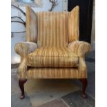 A Georgian style wing back armchair in striped and piped velour upholstery on cabriole supports. H.