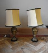 A pair of gilt brass classical design twin handled table lamps with cream shade and green fringe