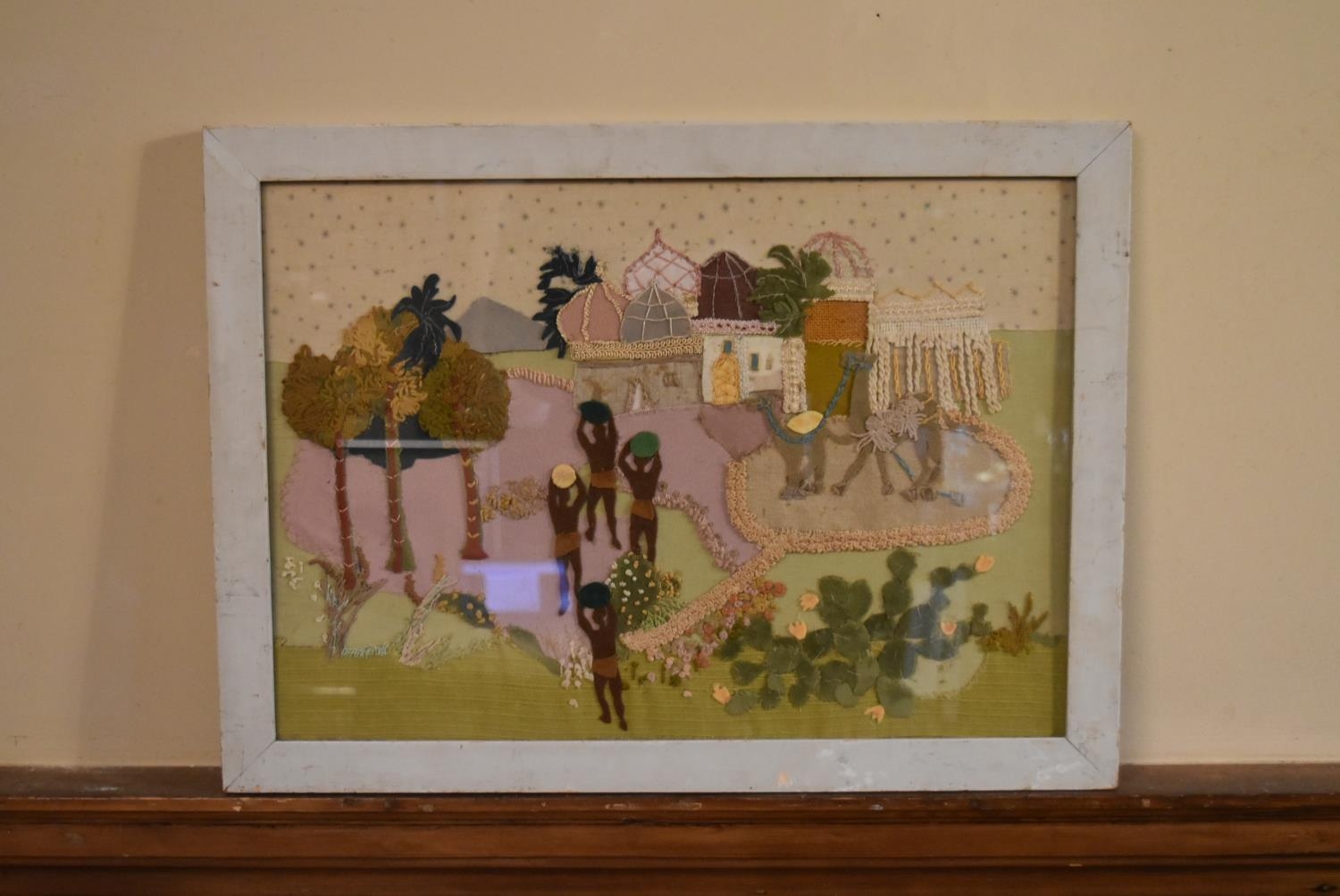 A framed and glazed embroidered panel, North African scene. H.43 W.58cm