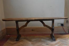 A 19th century fruitwood bench with shaped stretchers and trestle ends. H.45 W.135 D.20cm