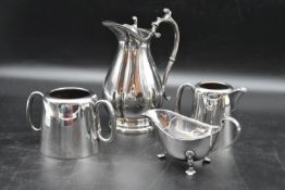 A collection of various silver plate tableware including a tall jug, twin handled pot, small milk