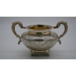 A Victorian twin handled silver sugar bowl with engraved decoration and foliate design handles and