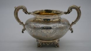 A Victorian twin handled silver sugar bowl with engraved decoration and foliate design handles and