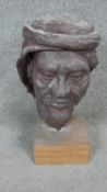 A sculpted ceramic head of a bearded man in a turban mounted on a wooden base. H.45cm