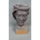 A sculpted ceramic head of a bearded man in a turban mounted on a wooden base. H.45cm