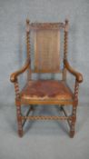 A mid century carved oak Carolean style armchair with caned back and leather seat on barleytwist