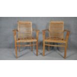 A pair of slatted teak framed garden armchairs. h93