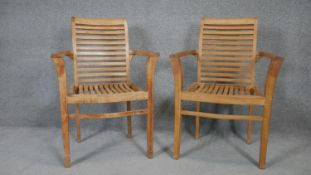 A pair of slatted teak framed garden armchairs. h93