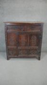 An 18th century carved oak panelled cupboard with drawers and a door on stile supports. H.117 W.