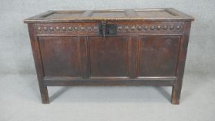 An 18th century country oak panelled coffer with carved frieze raised on stile supports. 74 w124 d58
