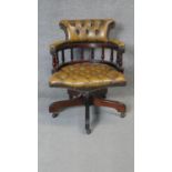 A mahogany framed revolving and tilting captain's desk chair in deep buttoned leather upholstery.