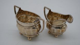 A silver sugar bowl and matching milk jug, with rope design edge and ball feet. Hallmarked: E&Dco