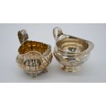 Two silver cream jugs. One Georgian with gadrooned form and foliate design handle, gilded