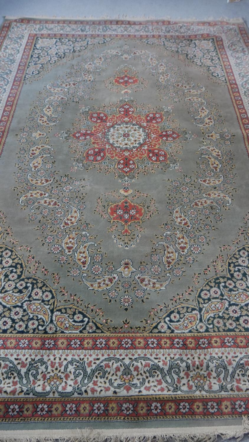 A Persian style woollen carpet with floral central medallion within foliate multiple borders.