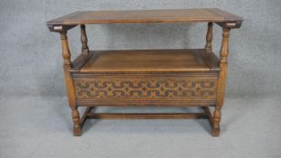 A mid century carved oak monk's bench in the antique style with sliding top to form an occasional