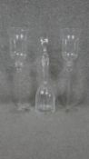 A pair of etched glass storm lanterns and a cut crystal decanter with stopper.