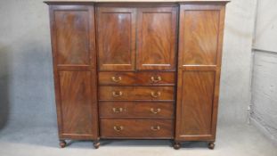 A mid 19th century figured mahogany three section compactum wardrobe fitted with drawers, cupboard