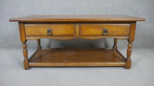 A mid century oak low table in the Jacobean style with magazine shelf to the base. H.47 W.107 D.54cm