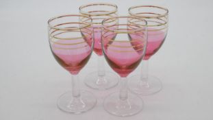 A set of four vintage painted pink wine glasses with gilded linear detailing and clear stems.