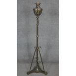 A Victorian brass floor standing oil lamp with tripod base and stylised foliate design. H.140cm