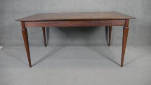 A teak and rosewood extending dining table with extra leaf raised on tapering shaped supports. H.