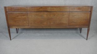 A teak and rosewood sideboard with satinwood strung frieze drawers above cupboard doors raised on