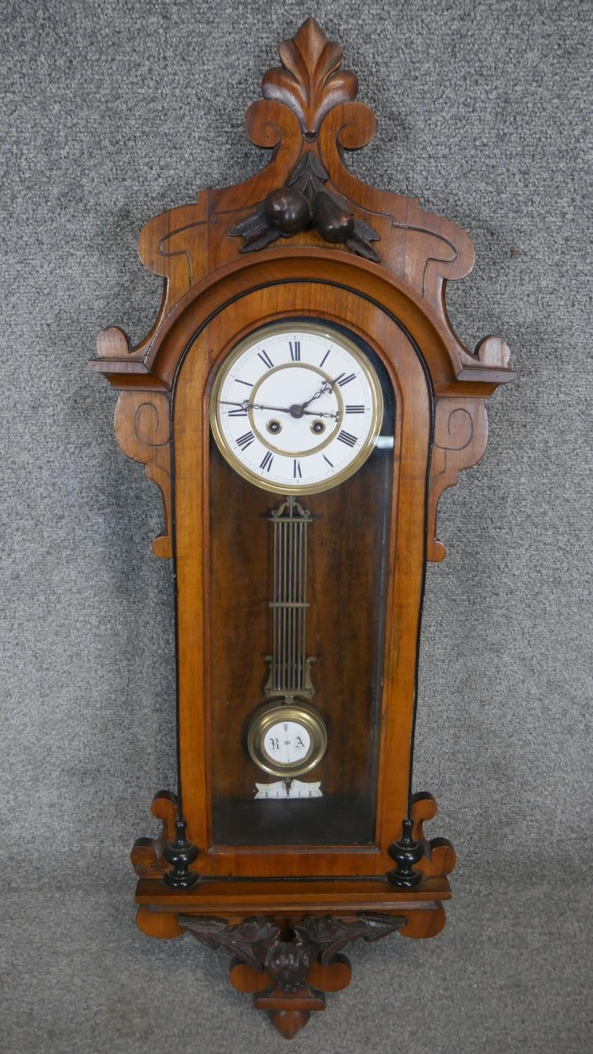 A 19th century Vienna regulator wall clock with eight day movement and white enamel dial in a carved