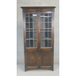 A mid century oak library bookcase with leaded glazed panel doors above cupboards. H.200 W.90 D.38cm