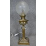 A converted Victorian brass oil lamp with fristed globe shade. The lamp has a fluted column design