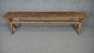 A vintage pitch pine bench on X framed stretchered supports. H.45 W.170 D.25cm