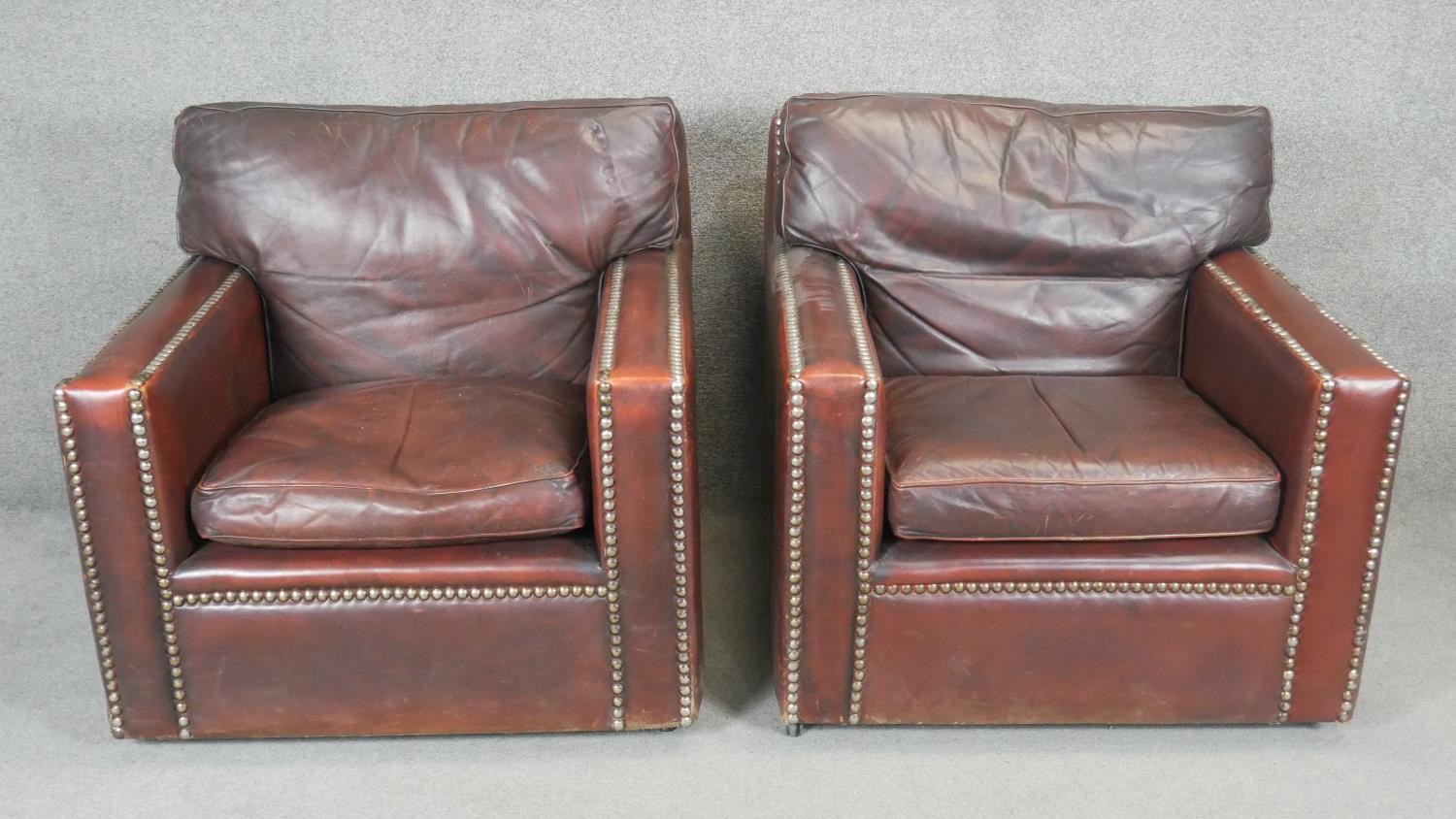 A pair of vintage library armchairs in studded tobacco leather upholstery.