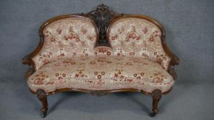 A Victorian carved walnut double chair back sofa in cut floral upholstery on cabriole supports. H.93