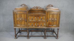A mid century oak Jacobean style sideboard with carved cresting above lozenge panelled doors on