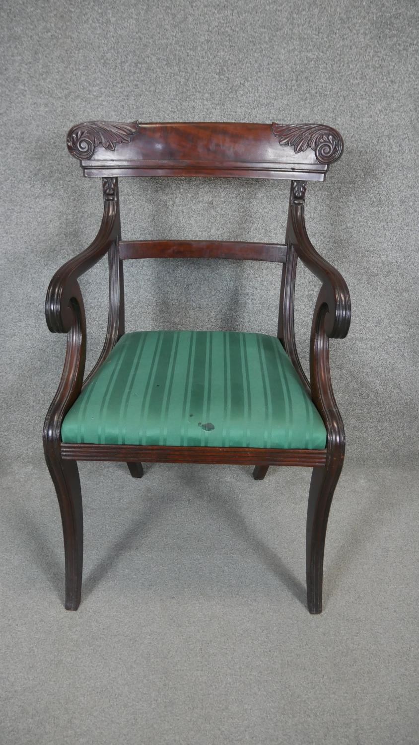 A Regency mahogany armchair with carved backrail and drop in seat on sabre supports.