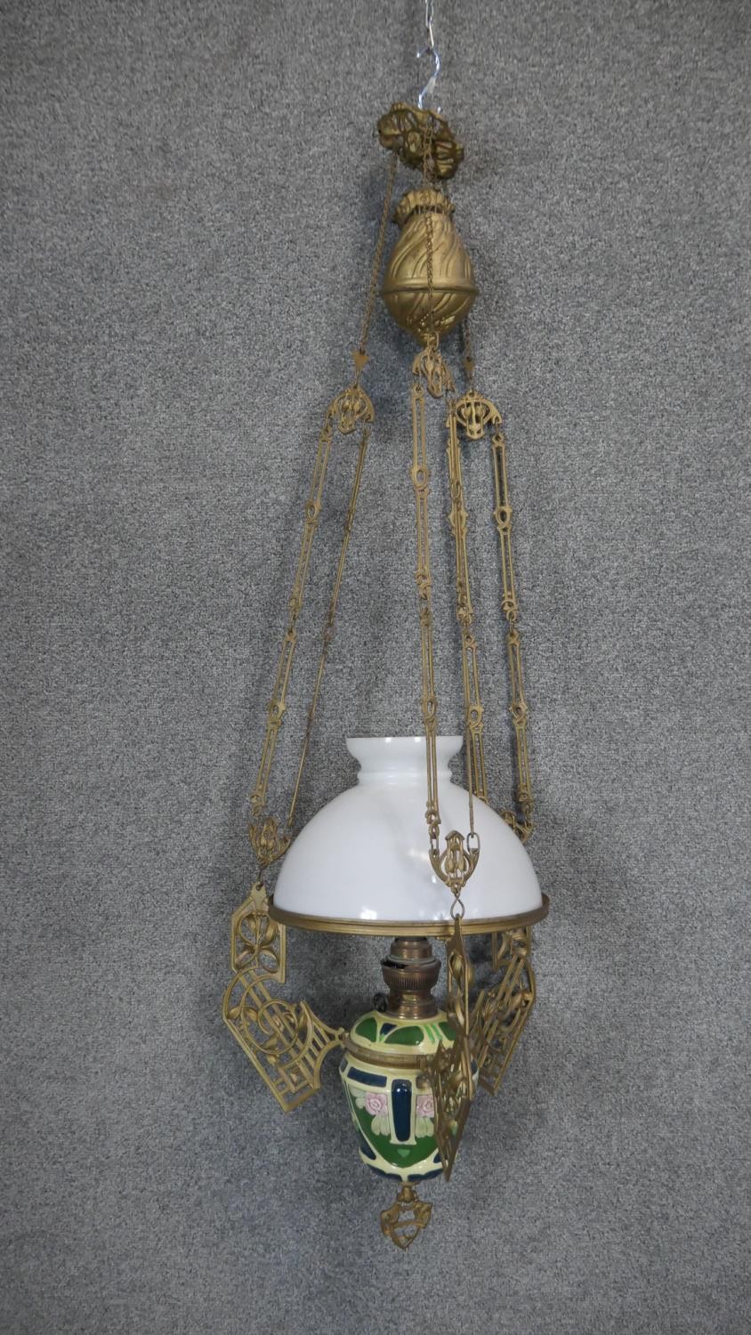 An Art Nouveau gilt metal and ceramic adjustable height oil lamp with weighted fitting. The