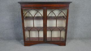 An early 19th century mahogany inlaid bookcase with astragal glazed doors on bracket feet. H.100 W.