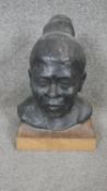 A sculpted ceramic head of a female with bun hairstyle mounted on a wooden block. H.35cm